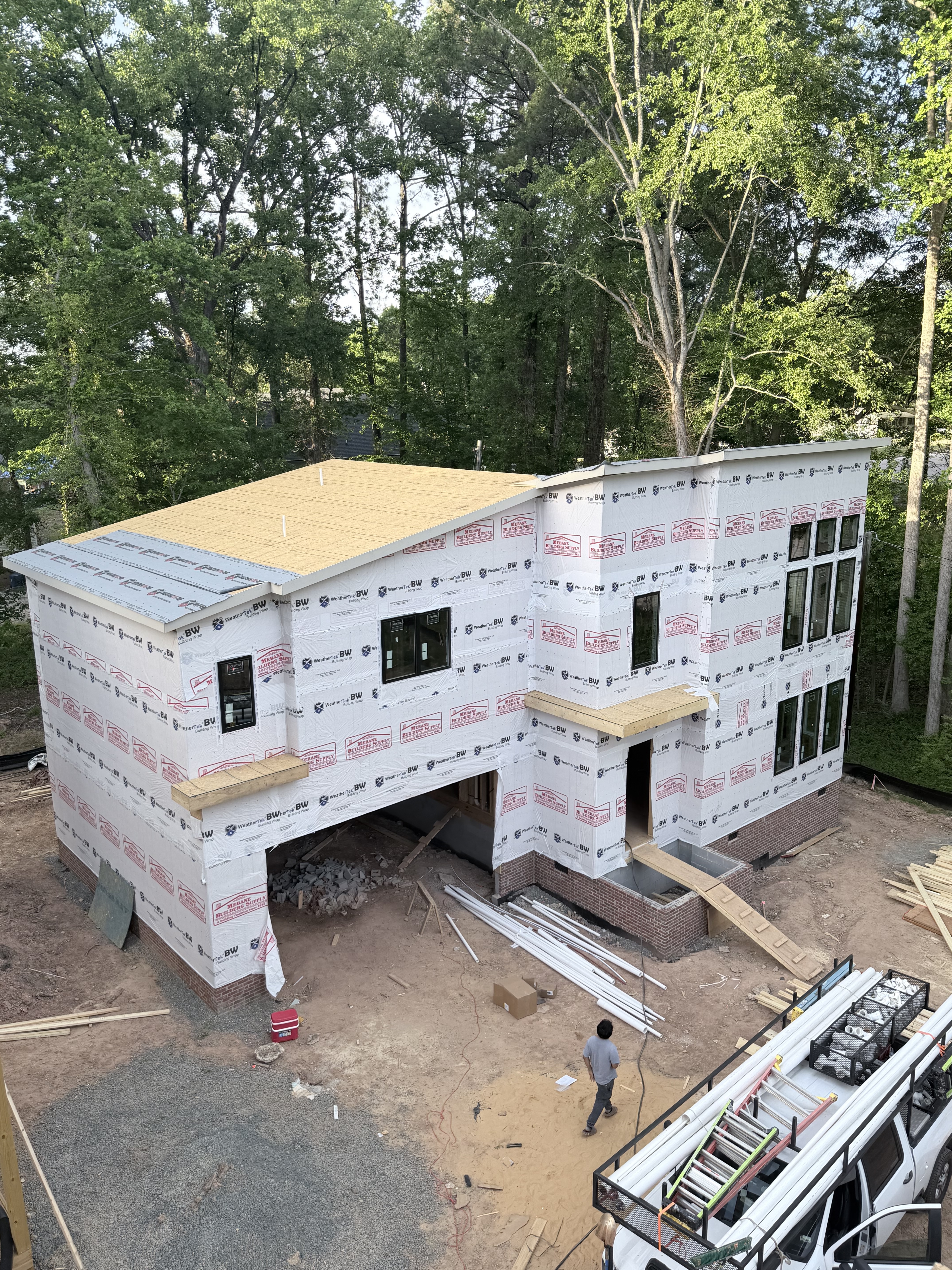 Elmira community street view — three modern homes under construction among Durham pines